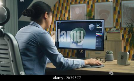 Designerin, die 3D Visualisierungen von Kleidung mithilfe von Computer und professioneller Software erstellt, während sie von zu Hause aus arbeitet Stockfoto