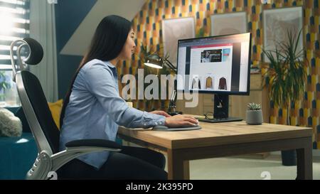 Weibliche asiatische Web-Designer mit Personal Computer für die Erstellung von Website in professionellen Konstruktor während der Arbeit an Projekt Remote zu Hause. Freiberuflich Stockfoto