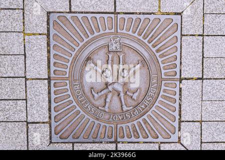 21. Juli 2022, Düsseldorf, Deutschland: Kanaldeckel oder Schachtloch mit Wappen oder Wappen von Düsseldorf an der Stadtstraße Stockfoto