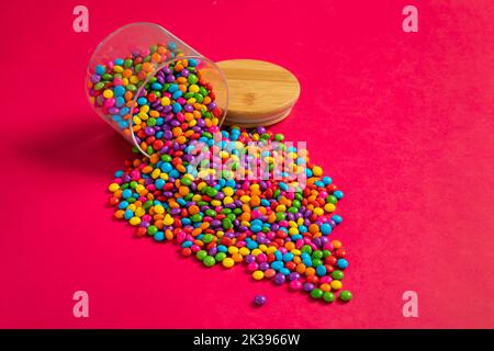 Verschiedene helle bunte Schokolade Süßigkeiten, Zucker beschichtete Schokolade Edelsteine Süßigkeiten. Schokoladenbonbon-Edelsteine auf buntem Hintergrund. Stockfoto