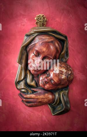 Rote Bas Relief madonna mit Kind in Umarmung. Stockfoto