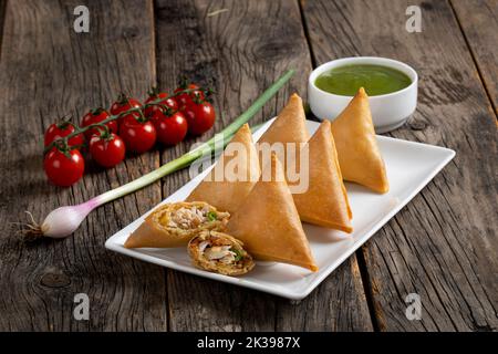 Süßes, leckeres, gebratenes indisches Gericht Samosha.Indisches köstliches tiefgebratenes Frühstück Samosa auch als Samoosa auf Holztextur Hintergrund isoliert bekannt Stockfoto