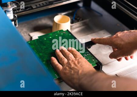 Europäischer Ingenieur während der manuellen SMD-Montage. Mensch und Maschine. Modernes Technologiekonzept. Reparaturvorgang der Leiterplatte. Hochwertige Fotos Stockfoto