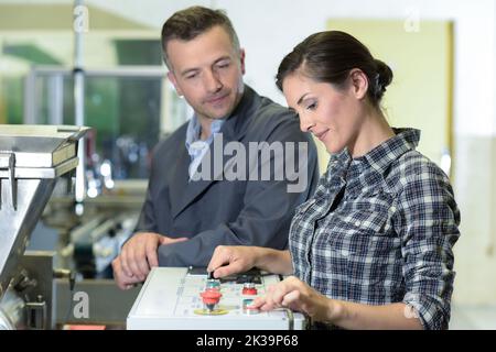 Ingenieur mit weiblichen Lehrling, wie eine Maschine zu bedienen. Stockfoto