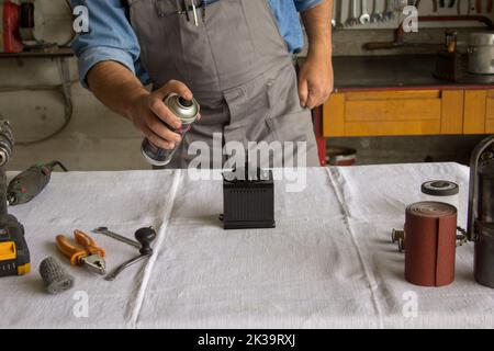 Bild der Hände eines Restaurators, der ein Vintage-Objekt mit einer Sprühdose malt. Stockfoto