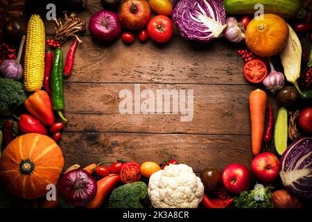 Rahmen aus Gemüse und Obst auf einem hölzernen Hintergrund. Rustikaler Hintergrund über frische Ernte und gesunde Lebensmittel. Stockfoto