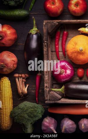 Herbsternte auf einem rustikalen Holztisch. Gemüse Aubergine Kürbis Zwiebel verschiedene Zutaten für Salat Rezept Küche Draufsicht. Stockfoto