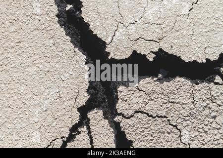 Ruinen auf der Straße. Gesprungener Asphalt. Tiefer Riss auf der Straße. Fehler in der Masse. Stockfoto