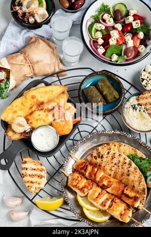 Griechischer Essenshintergrund. Meze, Gyros, Souvlaki, Fisch, Pita, griechischer Salat, Zatziki, Feta, Oliven und Fleischbällchen. Traditionell anderes griechisch Stockfoto