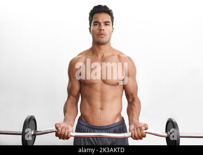 Aufbau seiner Oberkörperkraft. Studioporträt eines athletischen jungen Mannes, der eine Langhantel hebt. Stockfoto