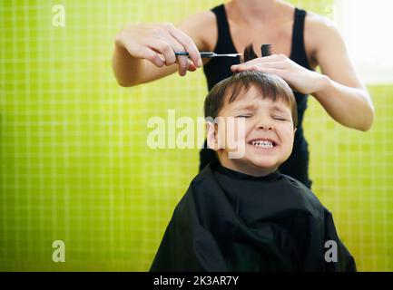 Sein erster Haarschnitt. Ein kleiner Junge bekommt seinen ersten Haarschnitt. Stockfoto