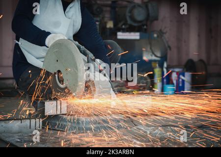 Schneiden des Stahls mit den Spritzern der Funken, Metallbearbeitung mit dem Winkelschleifer. Funken in der Metallbearbeitung. Stockfoto