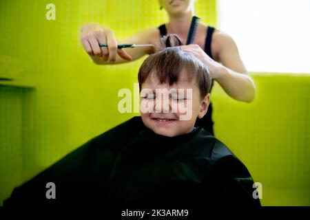 Dieser gefürchtete Haarschnitt im Schulalter... ein kleiner Junge bekommt seinen ersten Haarschnitt. Stockfoto