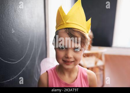 Ein nettes kleines Mädchen, das wie eine Märchenzeichnung auf einer Tafel gekleidet ist. Stockfoto