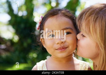 Die besten Freunde. Ein kleines Mädchen küsst ihre Freundin auf die Wange. Stockfoto