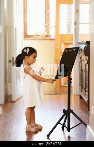 Natürliches musikalisches Talent. Ein kleines Mädchen, das Notation liest, während es die Blockflöte spielt. Stockfoto