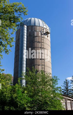 Nahaufnahme eines alten, runden Betonwandsilos mit einem Kuppeldach und blauem Himmel, der die natürliche Verwitterung von Alters her zeigt Stockfoto