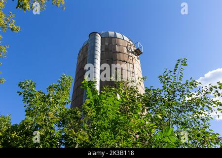 Nahaufnahme eines alten, runden Betonwandsilos mit einem Kuppeldach und blauem Himmel, der die natürliche Verwitterung von Alters her zeigt Stockfoto