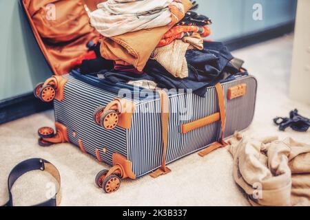 Öffnen Sie den Koffer voller Klamotten im Zimmer. Stockfoto