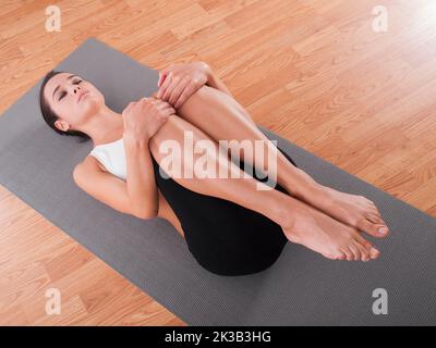 Sie nimmt sich immer Zeit für Yoga. Eine schöne junge Frau, die Yoga auf einer Übungsmatte macht. Stockfoto