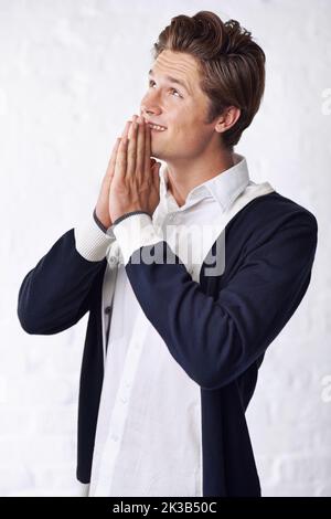 Ein hübscher junger Mann, der für einige Viel Glück. betet Stockfoto