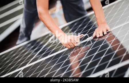 Mann Techniker Montage Photovoltaik-Solarmodule auf Dach des Hauses. Nahaufnahme des Elektrikers, der Solarpanel-System mit Hilfe des Sechskantschlüssels installiert. Konzept der alternativen und erneuerbaren Energien. Stockfoto