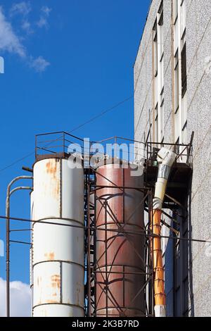 Industrierohre vom Ende des Gebäudes, rostige alte Rohre an der Seite der Fassade des Hauses Stockfoto