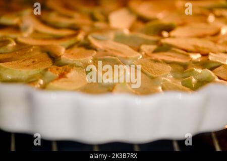 Apfelkuchen wird im Ofen auf einem Gericht gekocht. Der Prozess des Backens eines Apfelkuchen in einer Küche zu Hause Stockfoto