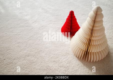 In rot und weiß gefertigte Bäume aus Papier. Sie werden auf einen weißen Wollteppich gelegt. Stockfoto