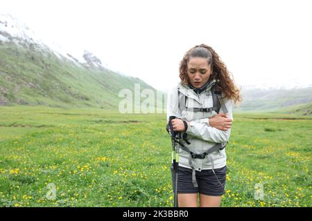 Vorderansicht Porträt eines gestressten Trekkers, der an einem nebligen Tag im Berg kalt wird Stockfoto