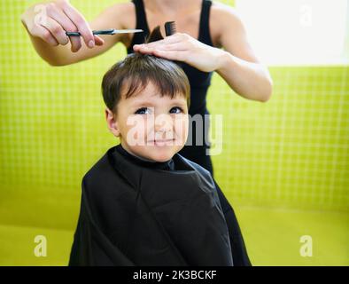 Warum brauche ich sogar einen Haarschnitt. Ein kleiner Junge bekommt seinen ersten Haarschnitt. Stockfoto