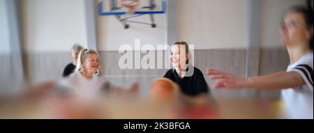 Frauen mit mehreren Generationen spielen im Fitnessstudio ein Basketballspiel. Stockfoto