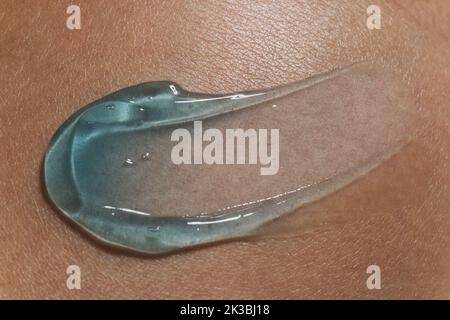 Gel-Serum auf dem menschlichen Hauthintergrund schmieren. Nahaufnahme, Draufsicht Stockfoto