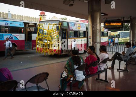 Ein farbenfroher Bus mit gelben Blumen an einem Busbahnhof in Mysore, Indien Stockfoto