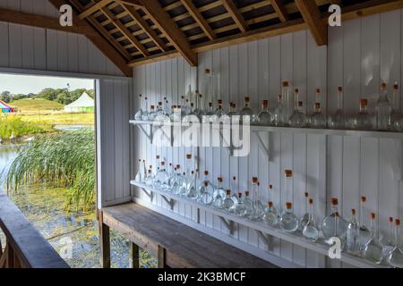 „Rivers“ von Tania Kovats enthält Wasserflaschen von 100 britischen Flüssen in einem Bootshaus auf dem Ententeich, Jupiter Artland, Wilkieston, Edinburgh. Stockfoto