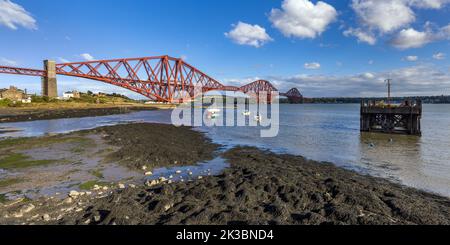 Ebbe am North Queensferry Harbour, mit der mächtigen Forth-Eisenbahnbrücke, die sich über den Firth of Forth erstreckt und den Norden und Süden von Queensferry verbindet. Stockfoto