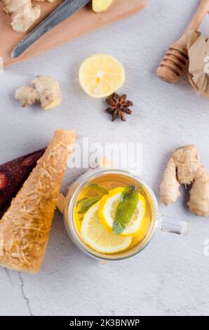 Heißer Tee mit Zitrone und Minze in Glas Tasse mit trockenen Früchten Lederrolle. Heißes Herbst- oder Wintergetränk. Das Konzept der Gesundheit. Stockfoto