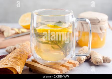 Heißer Tee mit Zitrone und Minze in Glas Tasse mit trockenen Früchten Lederrolle. Heißes Herbst- oder Wintergetränk. Das Konzept der Gesundheit. Stockfoto