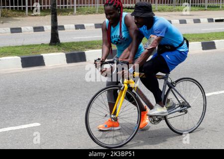 Lagos Feiert Den Weltautofreien Tag 2022 In Lagos, Nigeria. 25. September 2022. Ein Mann, der lernt, Fahrrad zu fahren, wird von einer Frau in Alausa unterstützt, als die Regierung des Staates Lagos am Sonntag, dem 25 2022. September, den 2022. Welt-Tag der autofreien Autos in Alausa, Ikeja, Lagos, Nigeria feiert. Die Landesregierung sagte, dass sie einen Fahrradparkplatz in einige ihrer Straßeninfrastruktur aufgenommen hat, um einen nicht-motorisierten Verkehrsplan zu fördern und die Fitness der Bürger zu verbessern. Quelle: Adekunle Ajayi/Alamy Live News Stockfoto