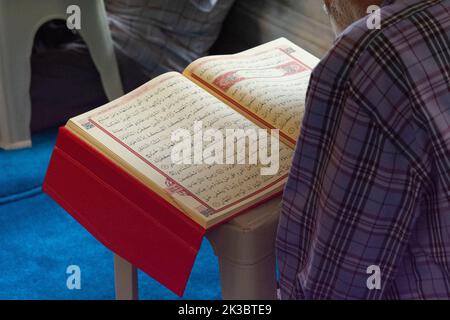 Mann beim Lesen des Quran in der Moschee, Islam und Religion Konzept, offene Koranseite, islamisches Filmmaterial, Glaube und Glaube, heiliges Buch, Beten und beten Idee Stockfoto