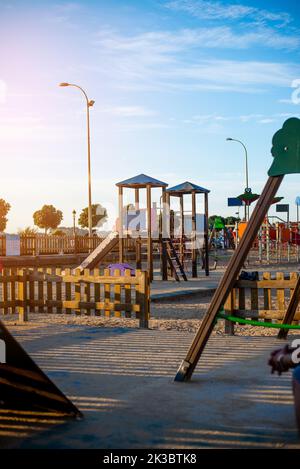 Öffentlicher Kinderspielplatz in Spanien aus Holz und Kunststoff bei Sonnenuntergang Stockfoto