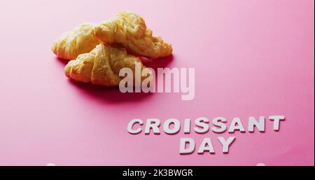 Bild von Nahaufnahme von Croissants und Croissant-Tag Text auf rosa Hintergrund Stockfoto