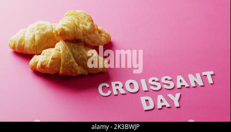 Bild von Nahaufnahme von Croissants und Croissant-Tag Text auf rosa Hintergrund Stockfoto