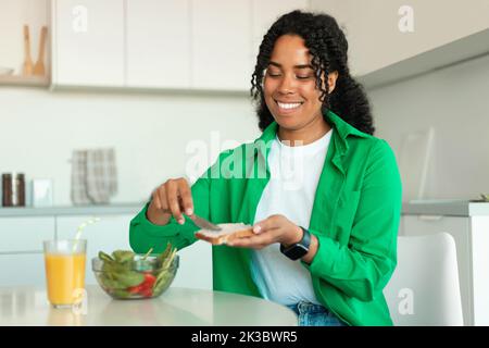 Happy African American Lady Essen Sandwich Mit Frühstück In Der Küche Stockfoto