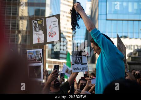 Vancouver, British Columbia, Kanada. 25. September 2022. Eine Frau schneidet sich die Haare zum Gedenken an Mahsa Amini, wie Tausende iranischer Kanadier am 25. September in der Vancouver Art Gallery demonstrieren. Amini, 22, starb am 16. September, während sie sich in Gewahrsam der iranischen˜-Moralpolizei befand, weil sie ihren Hijab angeblich zu locker getragen hatte. Neben weltweiten Demonstrationen gegen die Menschenrechtsverletzungen im Iran sagte ein Demonstranten in Vancouver, dass die Diaspora die Verantwortung habe, „˜ihre Stimme zu verwenden“, während iranische Demonstranten hinter einem Blackout im Internet zum Schweigen gebracht werden. (Bild: © Quinn Bender/ZUMA Press Wire) Stockfoto