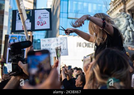 Vancouver, British Columbia, Kanada. 25. September 2022. Eine Frau schneidet sich die Haare zum Gedenken an Mahsa Amini, wie Tausende iranischer Kanadier am 25. September in der Vancouver Art Gallery demonstrieren. Amini, 22, starb am 16. September, während sie sich in Gewahrsam der iranischen˜-Moralpolizei befand, weil sie ihren Hijab angeblich zu locker getragen hatte. Neben weltweiten Demonstrationen gegen die Menschenrechtsverletzungen im Iran sagte ein Demonstranten in Vancouver, dass die Diaspora die Verantwortung habe, „˜ihre Stimme zu verwenden“, während iranische Demonstranten hinter einem Blackout im Internet zum Schweigen gebracht werden. (Bild: © Quinn Bender/ZUMA Press Wire) Stockfoto