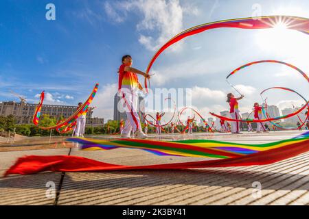 CHONGQING, CHINA - 26. SEPTEMBER 2022 - Menschen tanzen auf einem Platz zur aufgehenden Sonne Banddrachen für Fitness in Chongqing, China, 26. September 2022. Stockfoto