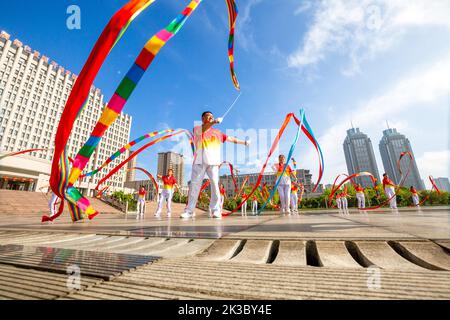 CHONGQING, CHINA - 26. SEPTEMBER 2022 - Menschen tanzen auf einem Platz zur aufgehenden Sonne Banddrachen für Fitness in Chongqing, China, 26. September 2022. Stockfoto