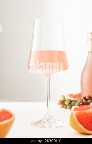 Ansicht von unten auf ein Glas mit Rosenperlwein, Trauben und Grapefruitscheiben mit einer Flasche Wein Stockfoto