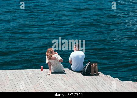 Ehepaar sitzt am Meer und unterhält sich in Karakoy, Mann und Frau streiten, blaues Meer in Karakoy, reden und kommunizieren Idee Stockfoto